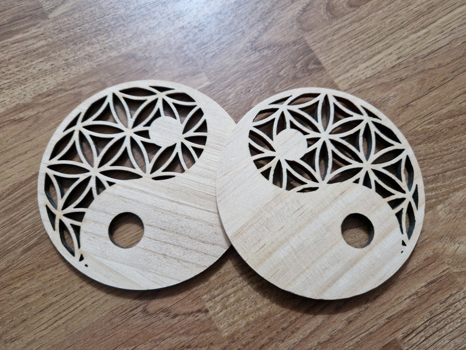 Two wooden coasters with intricate cut-out designs on a wooden surface.